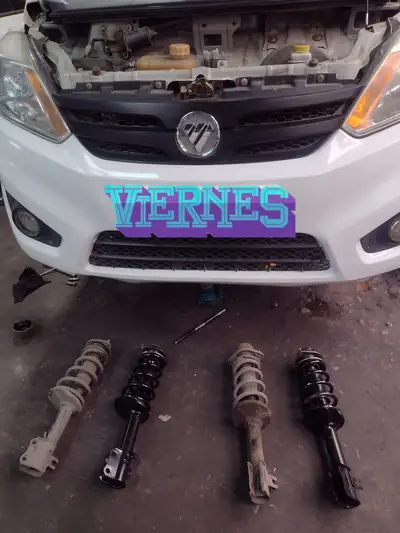 Foton en el taller con cuatro amortiguadores, dos viejos y dos nuevos