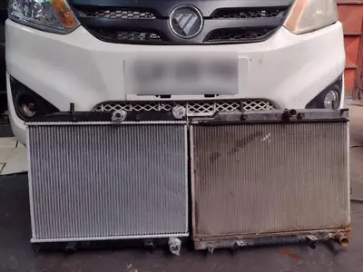 Foton Midi en el taller con el radiador nuevo y el viejo en el piso